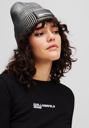 Juodas raštuotas marškinėliai su balta "KARL LAGERFELD JEANS" siuvinėjimu. Metalik sidabro spalvos megztas kepuraitė su plokščiu juodu logotipu.