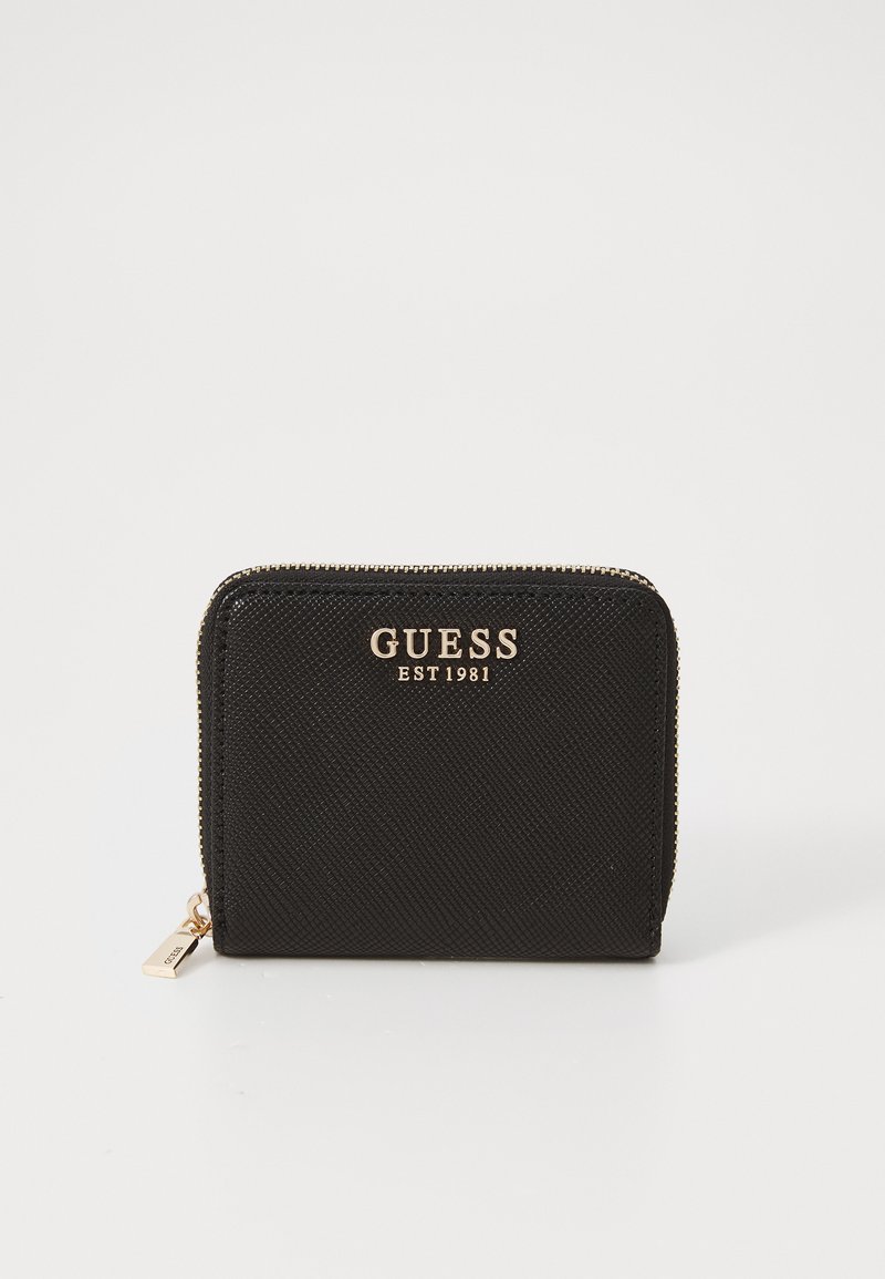 Portefeuille noir en matériau texturé, avec une fermeture éclair dorée, un logo doré "GUESS EST 1981" et une forme rectangulaire.