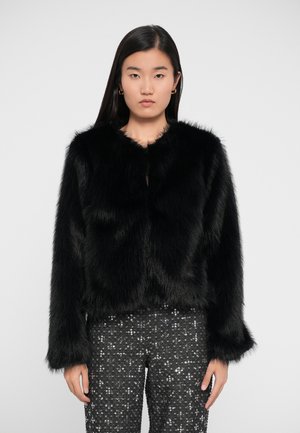 Black faux fur jacket with a rounded collar, long sleeves, and a cropped length. Worn over sequined black pants.