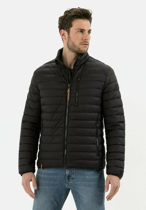 Black padded jacket with a high collar, featuring horizontal stitching, zippered pockets, and leather accents. Worn over a dark shirt.