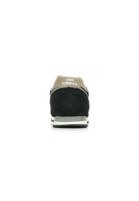Sneaker in suede nero con tallone in mesh grigio, logo bianco sul tallone e suola in gomma grigia. Design slanciato e accenti a contrasto.