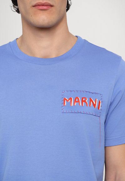 T-shirt en coton bleu avec un col rond, présentant une poche brodée rouge affichant "MARNI" avec des détails de couture contrastants.