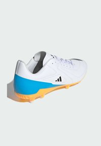 Hvid fodboldsko med blå detaljer og orange sål. Har en tekstureret overdel, der sikres af snørebånd, og et logo i sort. Bund med flere stifter.