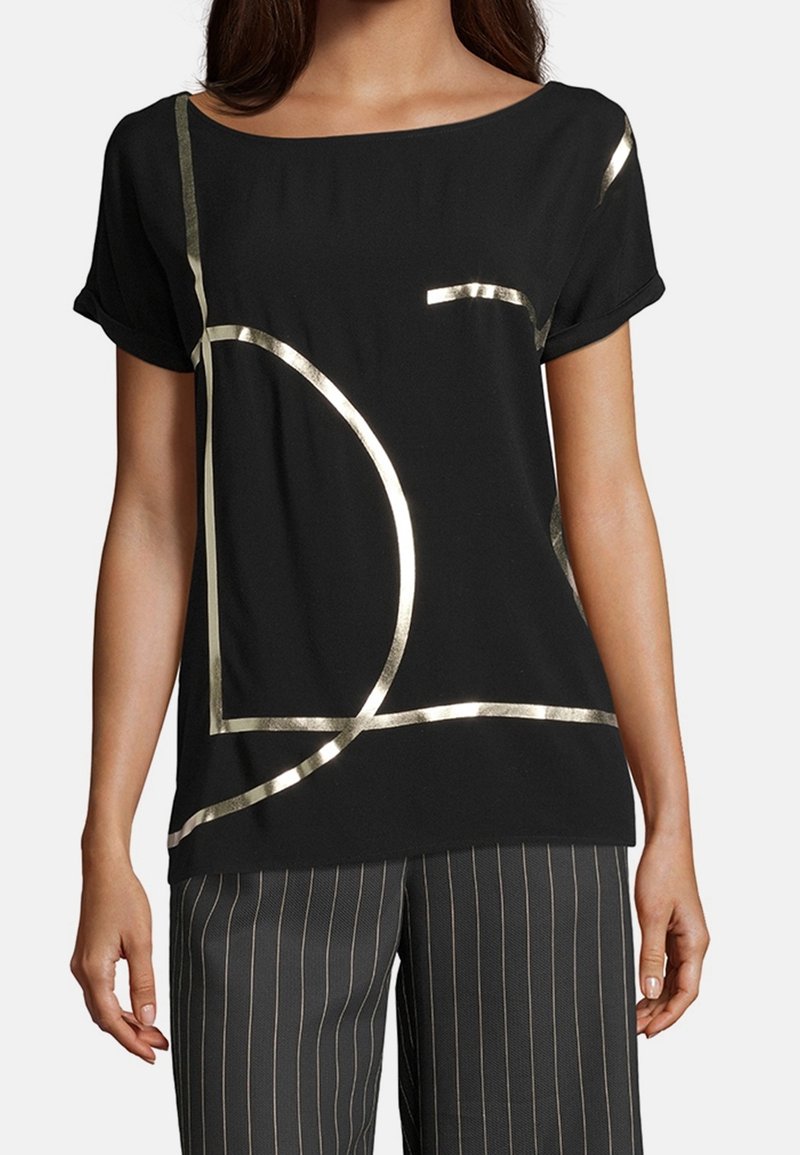 Top corto nero a maniche corte con design geometrici in oro metallizzato. Tessuto morbido con vestibilità comoda, scollo rotondo e accenti di lucentezza discreti.