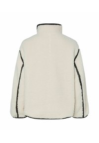 Chaqueta de forro polar color crema con cuello alto, ribete negro contrastante a lo largo de las costuras y diseño de ajuste relajado sin cierres visibles.