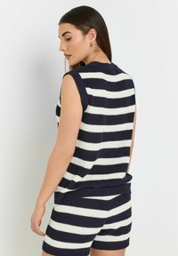 Marineblauwe en wit gestreepte gebreide mouwloze top met ribbelboord bij de hals en onderkant, gecombineerd met bijpassende gestreepte shorts. De textuur lijkt zacht.
