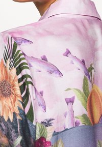 Seidenhemd mit floralem und aquatischem Design auf pinkem Hintergrund, sichtbaren Fischen, Sonnenblumen und tropischen Blättern, glatte Textur.