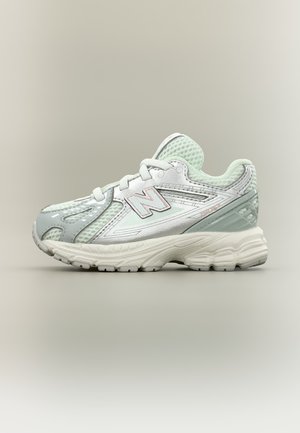 Weißer und hellgrauer New Balance Laufschuh mit Mesh-Obermaterial, gepolsterter Sohle und Schnürverschluss, seitlich auf neutralem Hintergrund gezeigt.