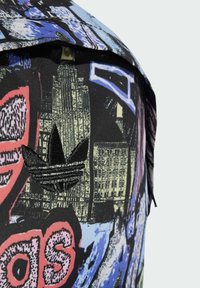 Zaino grafico con base nera e illustrazioni multicolori, tra cui edifici e motivi. Nota il logo ricamato in nero.