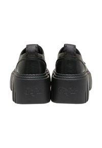 Černé platformové boty s tlustou robustní podrážkou, značky "Buffalo" na patě, zobrazené ze zadní strany na bílém pozadí.