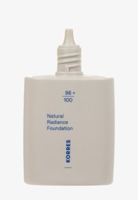 Die Natural Radiance Foundation in einer matten weißen Kunststoffflasche, versehen mit einer verjüngten Spritze und blauer Schrift mit der Aufschrift "95 + 100" und "KORRES."