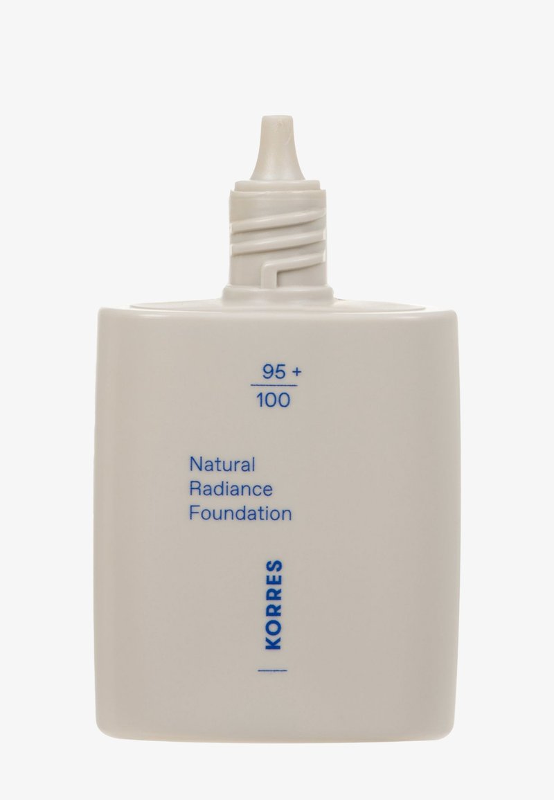 Die Natural Radiance Foundation in einer matten weißen Kunststoffflasche, versehen mit einer verjüngten Spritze und blauer Schrift mit der Aufschrift "95 + 100" und "KORRES."