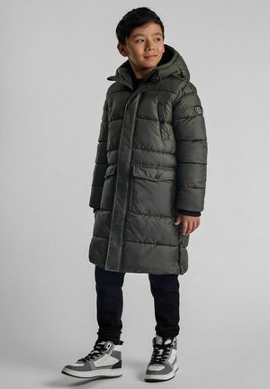 Žalias paminkštintas paltas su gobtuvu, su horizontaliu siuvimu, dviem priekinėmis kišenėmis ir logotipo pachu ant rankovės. Dėvima su juodomis kelnėmis ir sportbačiais.