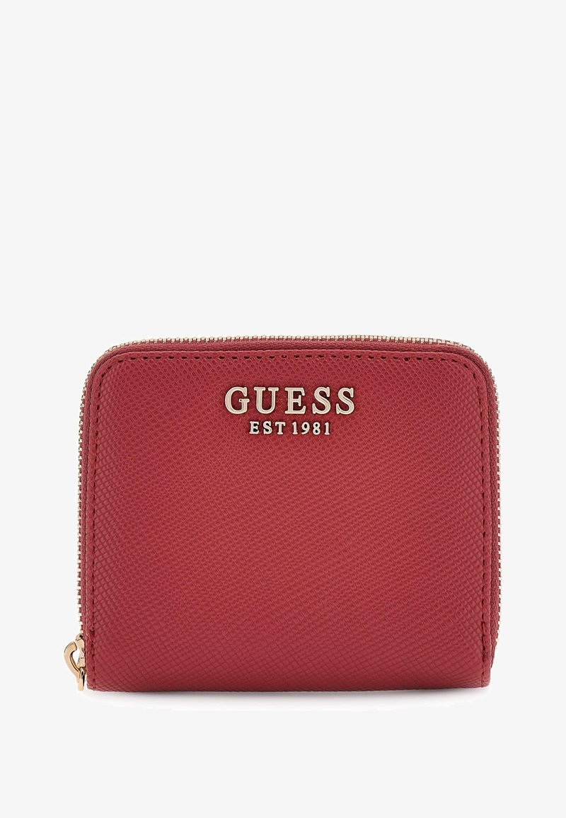Portefeuille rouge texturé avec fermeture éclair, présentant des éléments en or et "GUESS EST 1981" embossé sur l'avant. Forme rectangulaire.