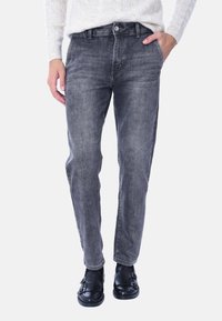 Jeans in denim grigio con taglio dritto, cinque tasche e una leggera sfumatura. Abbinati a scarpe nere con due dettagli a fibbia.