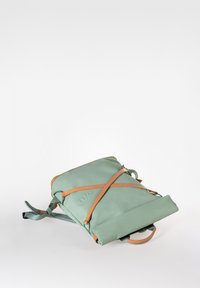 Hellgrüner Rucksack mit sandfarbenen Lederriemen, quadratischer Form, glatter Textur und einem oberen Griff. Verfügt über ein minimalistisches Design und verstellbare Riemen.
