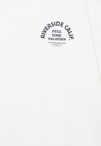 Chemise blanche avec texte noir indiquant « Riverside Calif. Full Time Vacation Crenshaw Boulevard Los Angeles 3773 Calif. » sur la partie supérieure gauche de la poitrine.