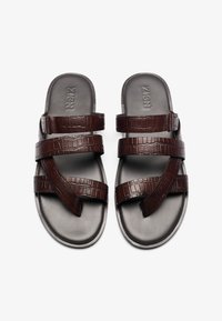 Brown crocodile-embossed sandals with three overlapping straps and flat soles. Smooth texture with a matte finish. Logo on insole.