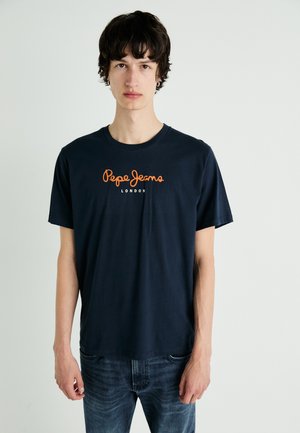 Mørkeblå t-skjorte med korte ermer og rund hals, med oransje "Pepe Jeans London" logo trykket på forsiden. Stoffet ser mykt og glatt ut.