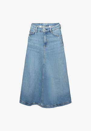 Vrouw draagt een oranje mouwloos topje, een lichtblauwe denim midi rok en zwarte open-toe sandalen, staand tegen een witte achtergrond.
