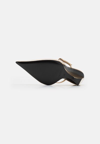 Zapato de tacón alto negro con correa al tobillo que presenta una punta afilada, suela texturizada y acentos dorados; diseño elegante con curvaturas y un tacón delgado.