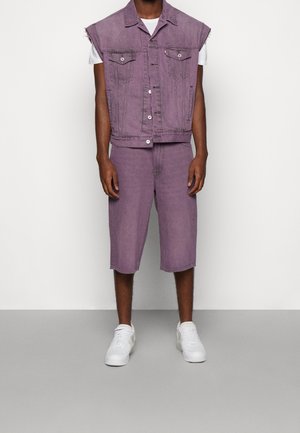 Lila Jeansweste und passende Shorts, die eine lockere Passform, ausgefranste Ärmel und weiße Sneaker aufweisen. Einfaches Design mit minimalen Details.