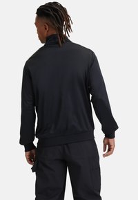 Zwarte zip-up jas met hoge kraag, lange mouwen en elastische manchetten. Soepele textuur, aansluitend ontwerp, geen zichtbare patronen of accenten.