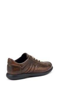 Baskets en cuir brun avec finition texturée, bout arrondi et semelle en caoutchouc noir. Elles présentent des lacets beige et des détails latéraux subtils.