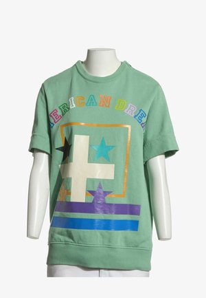 Sweat-shirt vert à manches courtes avec des lettres colorées formant le mot "AMERICAN DREAM" et des motifs géométriques d'étoiles et de rayures sur le devant.