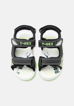 Gyermek fekete és zöld nyitott orrú szandál "T-REX" pántokkal, fehér, dinoszaurusz témájú talpbetétekkel, csillagokkal és koponya grafikákkal.