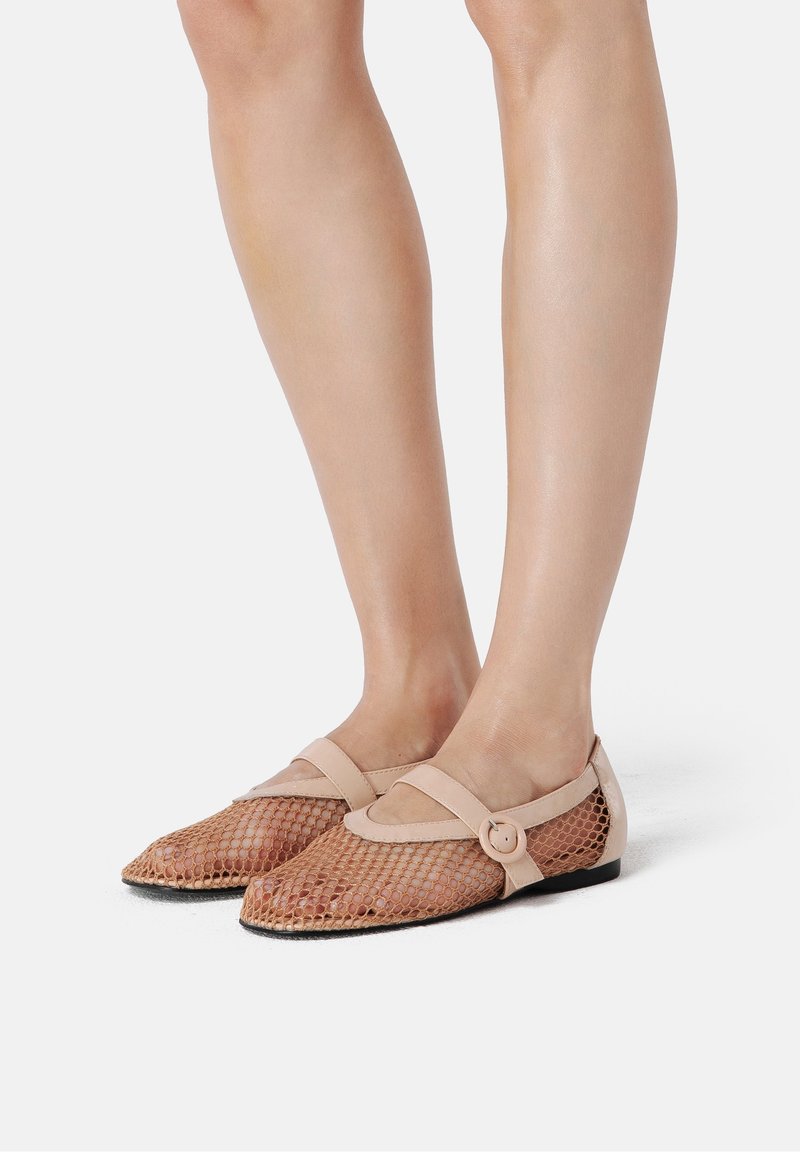 Ballerines en mesh beige avec bout pointu, semelle plate et une bride décorative ornée d'une boucle ronde. Design ouvert pour une meilleure respirabilité.