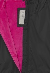 Chaqueta negra con capucha y una textura exterior suave; forro suave en color rosa. Presenta una etiqueta con la palabra "Chica" y la información de tallas.