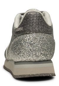 Grå träningsskor med en glittrig silverfinish, texturerad mörkgrå bakdel, mjukt vitt foder och en ljusgrå gummisula.