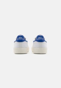 Fehér sportcipők kék részletekkel és "new balance" márkázással a saroknál. Simább felsőrésze és texturált talpa van.