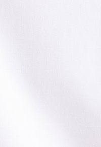 Een persoon in een witte overhemd met knopen en een zwart polshorloge houdt een blanco wit schoolbord met houten frame vast.