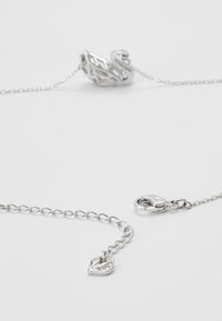 Silver necklace featuring an intricate swan pendant and a small charm. The chain has a polished finish with a secure lobster clasp closure.