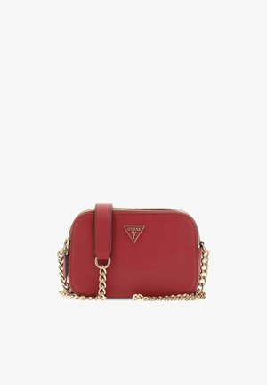 Sac bandoulière rouge Guess avec sangle chaîne dorée et plaque logo triangulaire à l'avant, forme rectangulaire aux bords arrondis avec fermeture éclair.