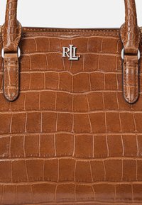 Mala castanha com padrão de crocodilo, apresentando duas alças resistentes e um accentuador prateado com o logo "RL". Textura suave com costura em contraste.