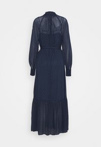 Námořnická modrá šaty s dlouhým rukávem s bílými puntíky, vysokým límcem, staženým pasem a vrstveným volánkovým lemem. Lehce průhledná tkanina.