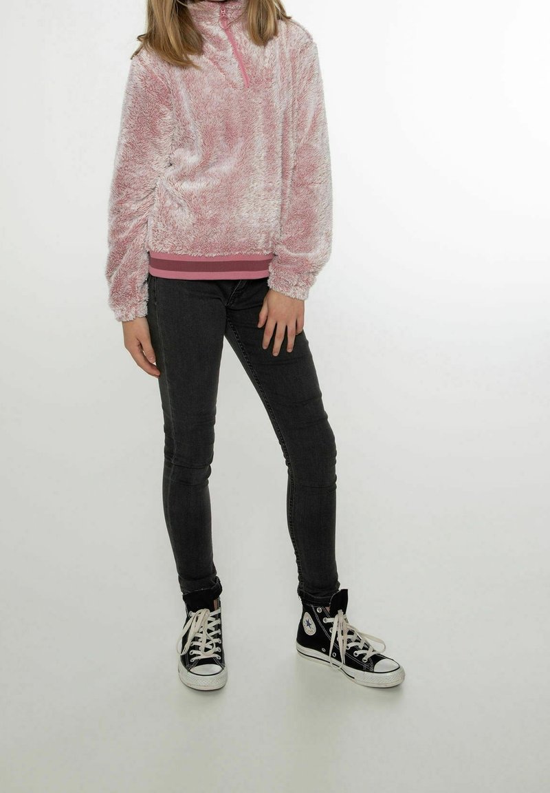 Pull-over rose duveteux avec un col demi-fermeture éclair et un ourlet côtelé rose, assorti à un jean noir slim et des baskets montantes noires.