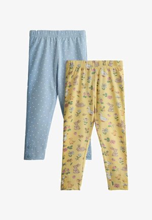 Dwie pary legginsów dziecięcych, jedne jasnoniebieskie w białe kropki z guzikami przy kostkach, drugie żółte z nadrukiem zwierząt i kwiatów.