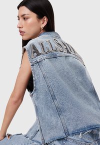 Denim prsluk u svijetloplavoj boji s neurednim rubom i ukrašenim natpisom "ALLSAINTS" na leđima. Ima dizajn bez rukava i izblijedjeli izgled.