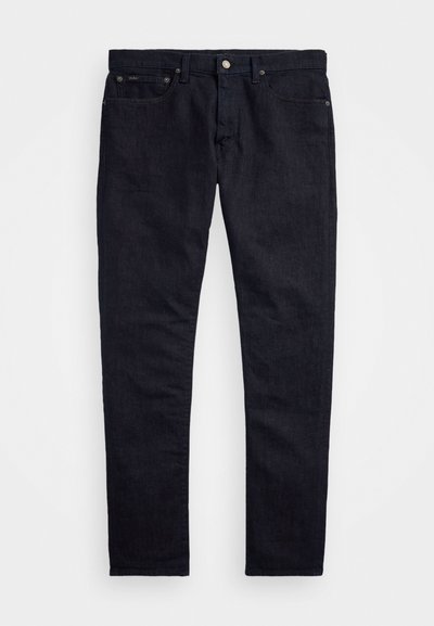 Pantalon en denim bleu foncé avec une coupe slim, un design à cinq poches et une fermeture à bouton en métal. Jambes droites et détails de couture minimalistes.