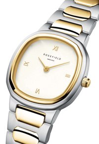 Reloj cuadrado con pulsera de acero inoxidable en plata y oro. Esfera blanca con marcadores de hora dorados. Nombre de la marca "ROSEFIELD" debajo de las 12 en punto.