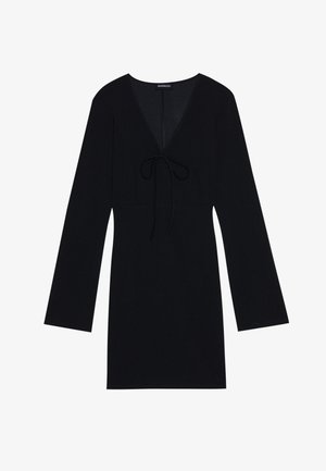 Black dress made of soft fabric, featuring a V-neck, long sleeves, and a tie detail at the front. Simple design, above-the-knee length.