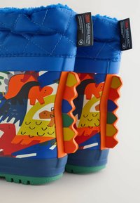 Kleurige kinderlaarzen van rubber, met een gewatteerde blauwe bovenkant, speelse dierenpatronen en textuuraccenten in oranje aan de zijkanten.