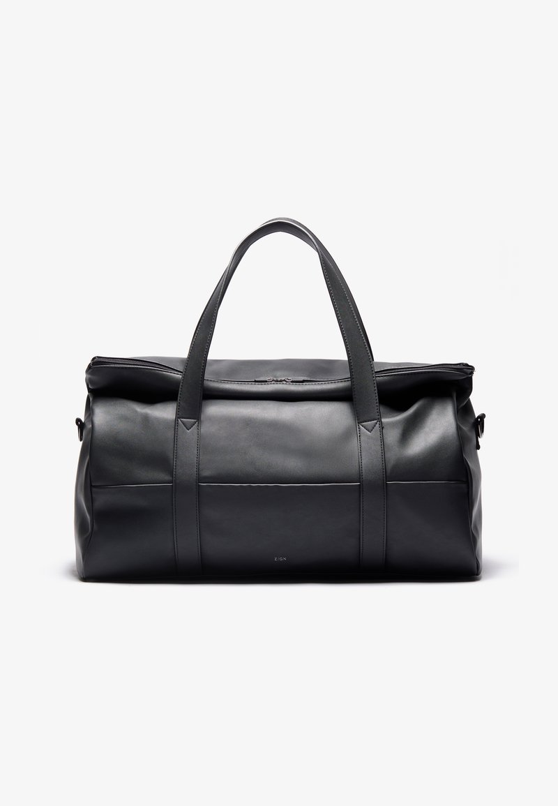Borsa da viaggio in pelle nera con doppi manici superiori, chiusura con zip e texture liscia. Presenta un logo discreto e un design minimalista.