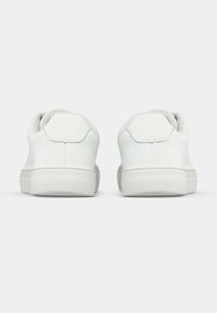 Λευκά αθλητικά παπούτσια με λείο δέρμα στην κορυφή, στρογγυλή μύτη και επενδεδυ�μένο κολάρο. Υφασμάτινη σόλα από καουτσούκ και ελάχιστες ραφές.