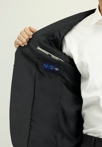 Blazer nero con una fodera interna liscia. Presenta una tasca interna etichettata "Polo Club". Esterno testurizzato e dettagli di sartoria classici.