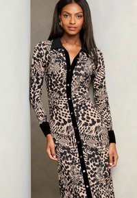 Abito con maniche lunghe e bottoni in stampa animale beige e nera, dotato di colletto e polsini neri, texture liscia e silhouette aderente.